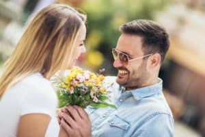 Picture of young man surprising woman with flowers